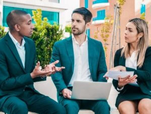 Image of three people having a meeting outside.