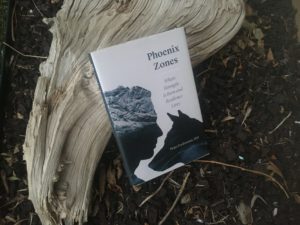 Image of the book Phoenix Zones leaning up against a piece of wood.