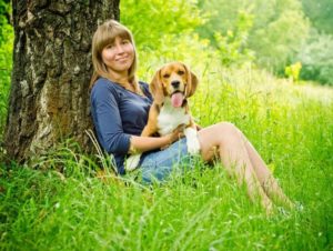 young person with a dog in their lap sitting under a tree