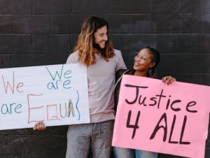 Two people holding social justice signs and smiling at each other
