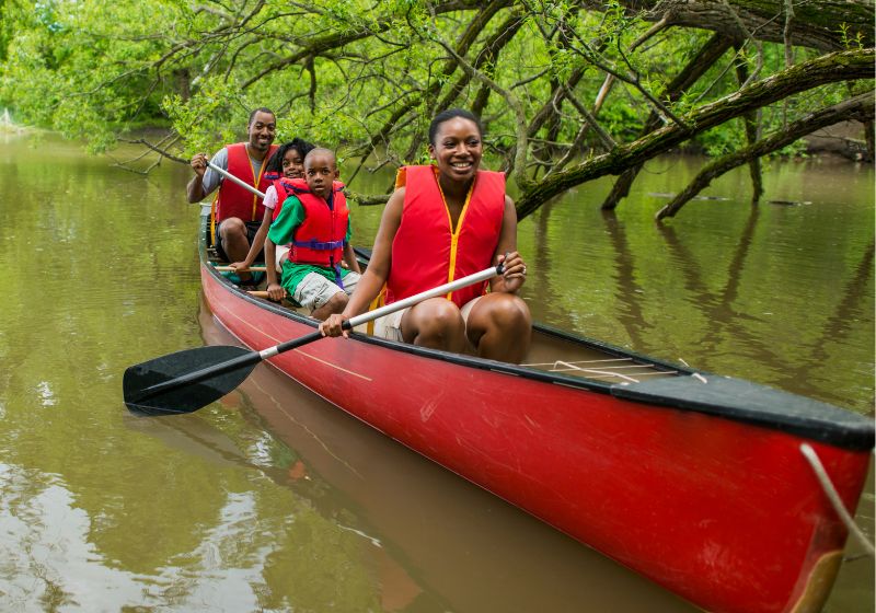 Image of a Black family paddling a canoe.