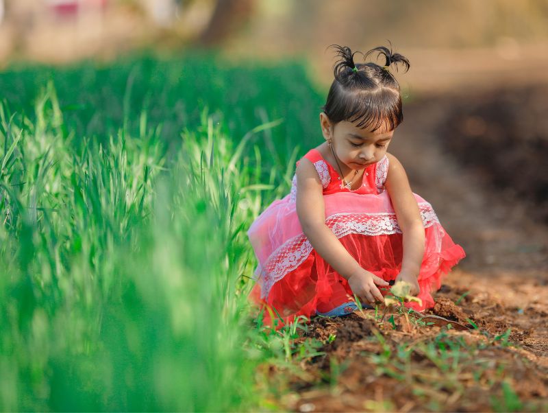 A child sitting next to a field--we need to protect children from pesticide poisoning
