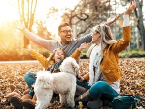 Smiling family with dog playing outside--all beings deserve a right to health