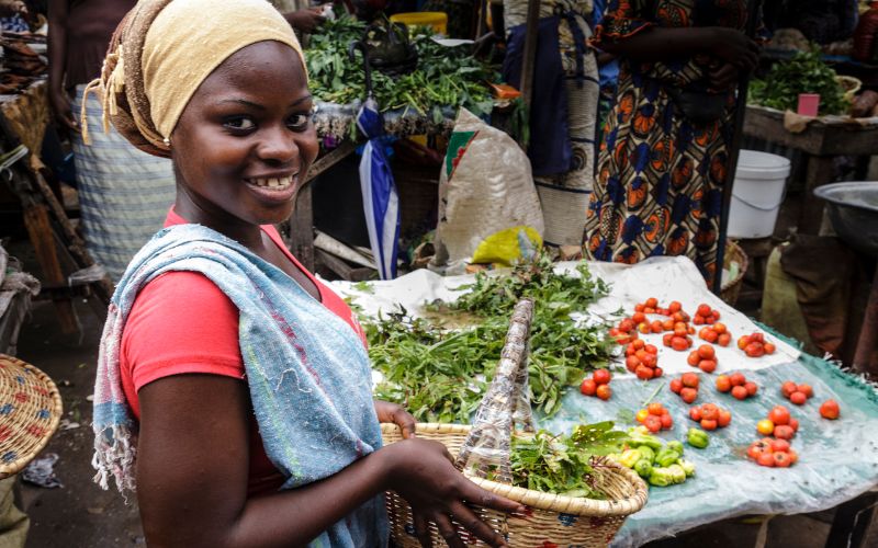 A woman holding a basket full of vegetables at a farmer's market--we need an ethical, sustainable food policy