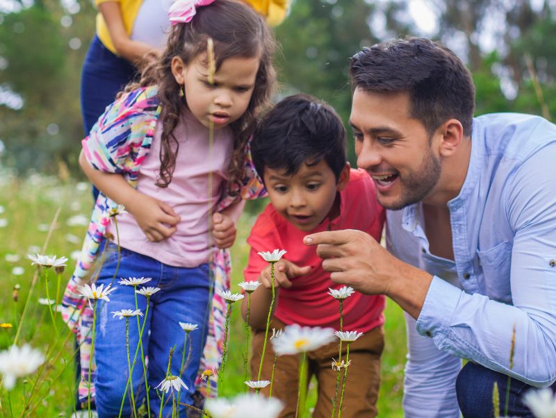 A family looks at a bug on a flower--we need a socially and ecologically just One Health approach